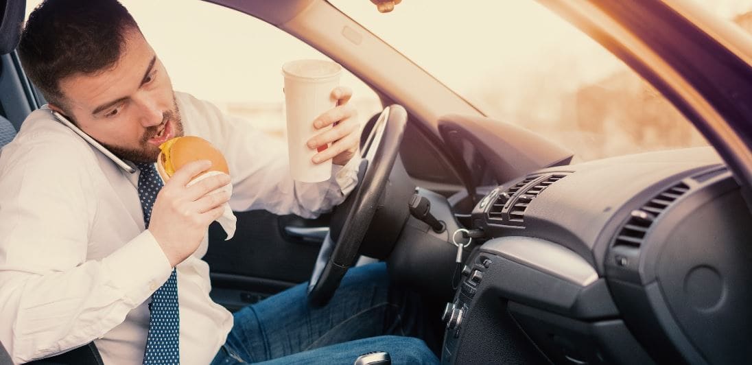 Man tries to drive while he's eating and talking on the phone